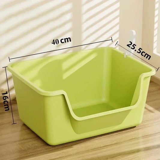 Green plastic pet litter box with dimensions on a wooden floor.