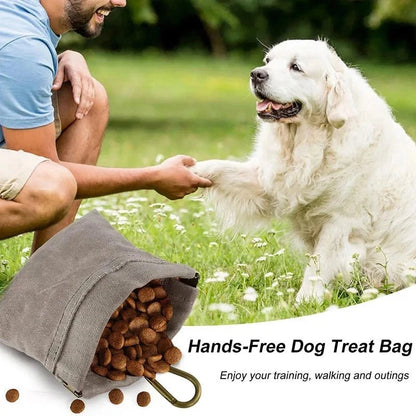 Man kneeling in grass with a white dog, holding a 'Hands-Free Dog Treat Bag' open with treats spilling out.