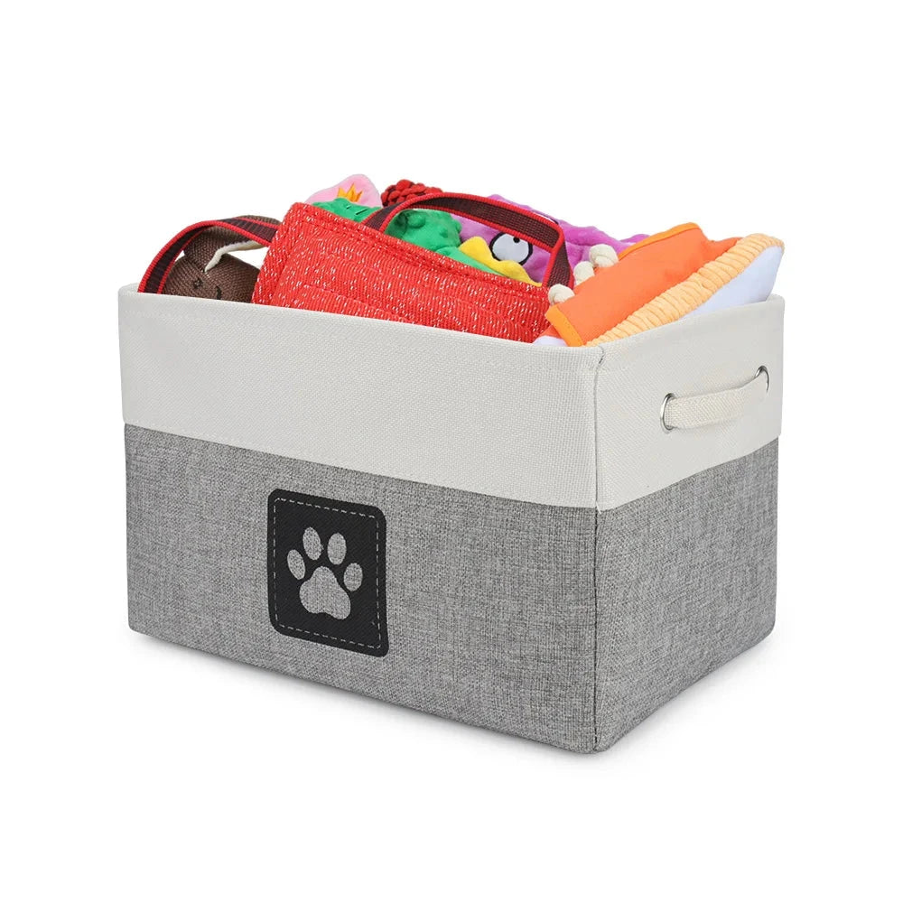 Gray storage bin with a paw print logo filled with colorful pet toys on a white background