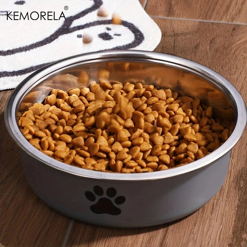 Stainless steel dog bowl filled with kibble on a wooden floor, brand 'KEMORELA' visible.